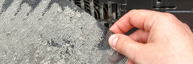 Dirty computer case. A layer of dust on the system unit. Time to clear your computer of dust. Dusty mesh from the computer in hand.