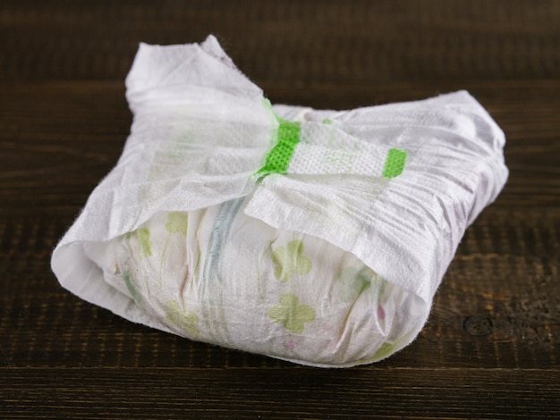 Dirty diaper on dark wooden background