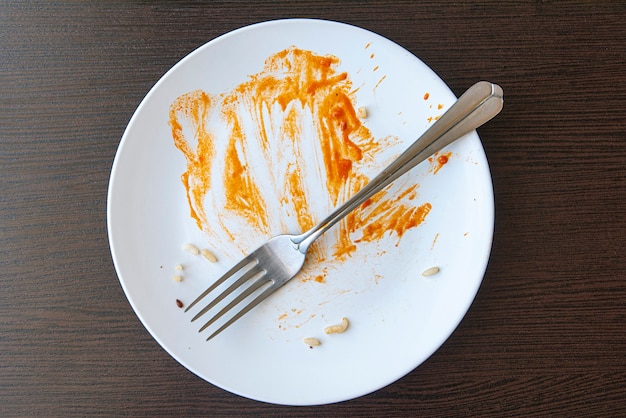 사진 빨간 소스와 함께 음식 잔해와 더러운 접시. 흰 접시와 포크 테이블에.