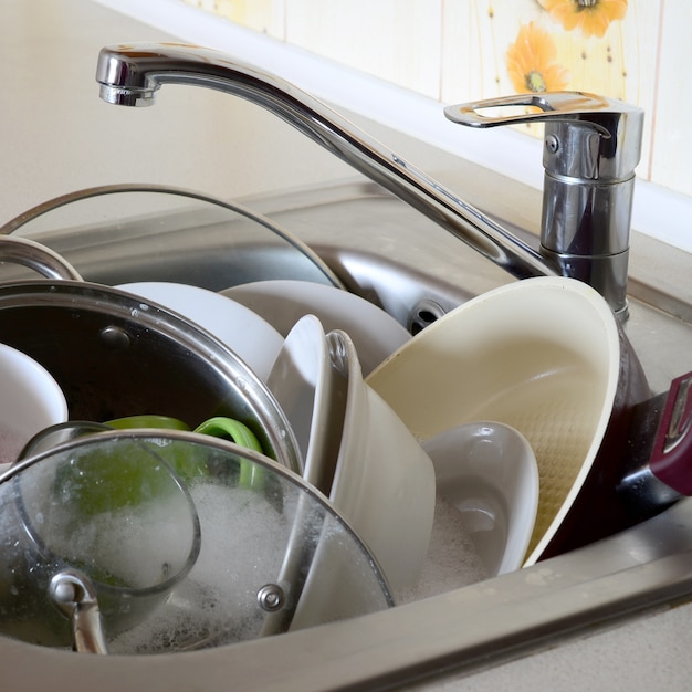 Photo dirty dishes and unwashed kitchen appliances filled the kitchen sink