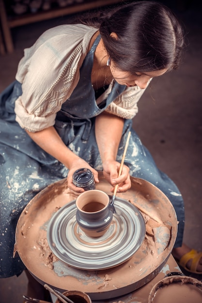 Dirty hands in the clay and the potter's wheel with the product