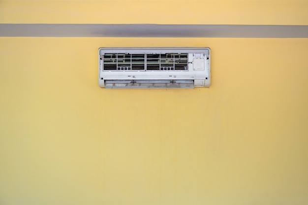 사진 더러운 현대식 에어컨은 패널을 열어 노란색 벽에 있는 기계 내부의 먼지를 청소합니다