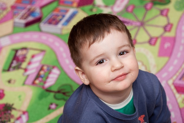 Dirty mouth of a little child boy sitting on the playing ground and smiling