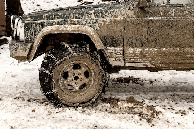 Photo dirty off road car with chain on tire on the snow