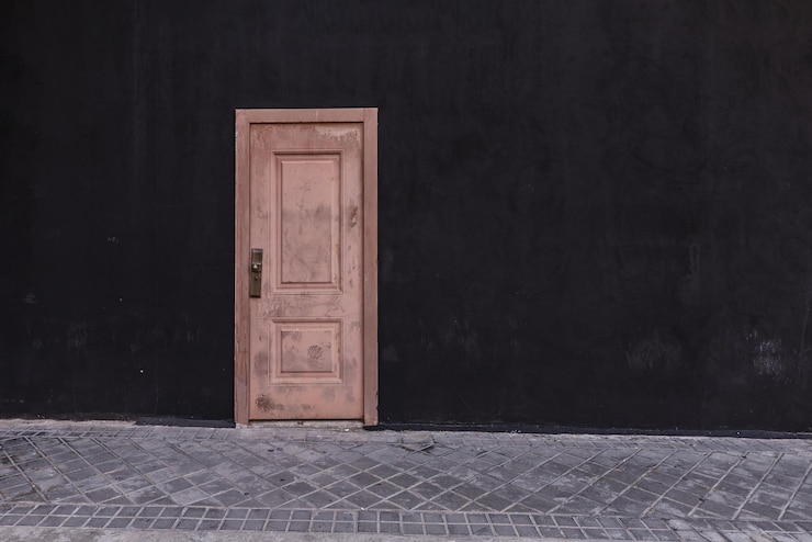 Photo dirty pink door on a street with a black wall