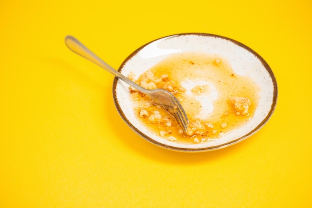 Dirty plate with honey and pie crumbs on yellow background