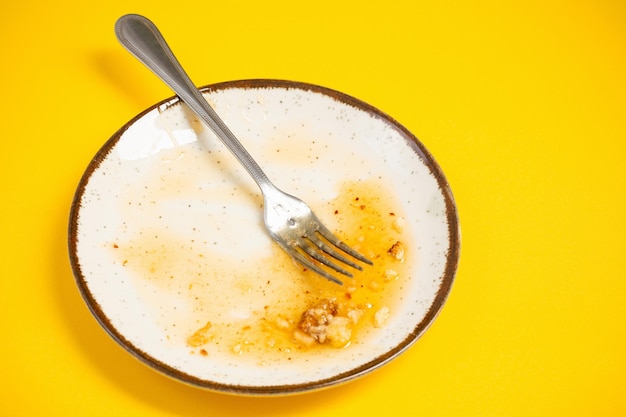 Dirty plate with honey and pie crumbs on yellow background