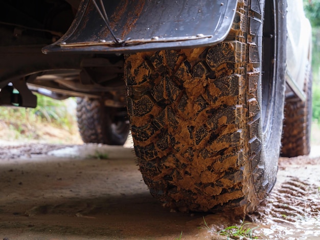 Ruota posteriore sporca del camion fuoristrada 4x4 in un luogo rurale di campagna in atmosfera piovosa, veicolo 4wd sotto la pioggia, messa a fuoco selettiva profondità di campo ridotta