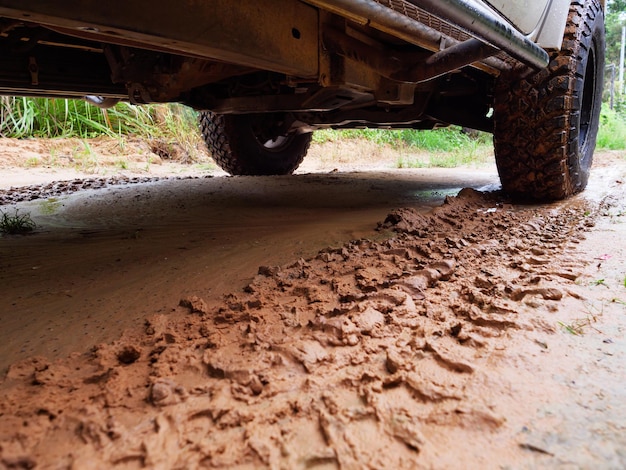 Ruota posteriore sporca del camion fuoristrada 4x4 in un luogo rurale di campagna in atmosfera piovosa, veicolo 4wd sotto la pioggia, messa a fuoco selettiva profondità di campo ridotta