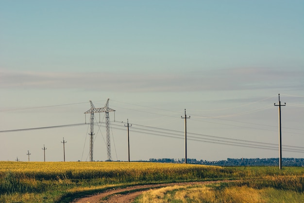 Photo dirty road through field under electric wires.