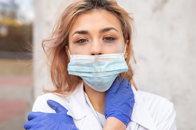 Dirty tired nurse with ash on face sitting outside
hospital