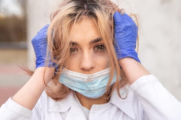 Dirty tired nurse with ash on face sitting outside hospital