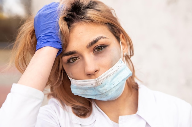 Dirty tired nurse with ash on face sitting outside\
hospital