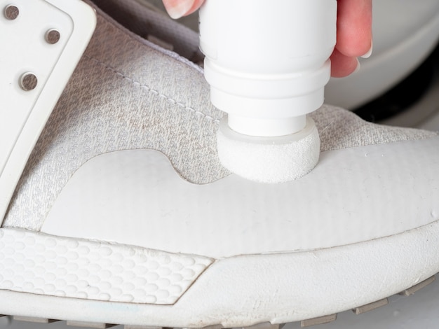 Dirty white sneakers are cleaned with a close-up tool. Concept of Shoe care at home