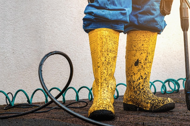 Foto scarpe di gomma gialle sporche dopo aver pulito il pavimento con uno spruzzatore d'acqua