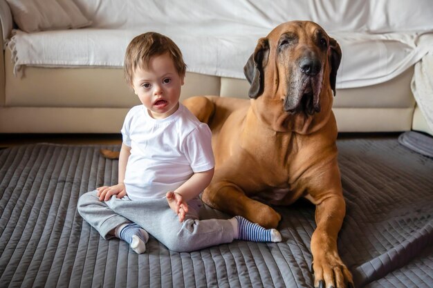 写真 家のカーペットの上に座っている犬を持つ障害のある男の子