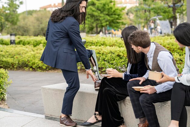 Disabled businessman adjusting his prosthetic leg outside the\
office with coworkers