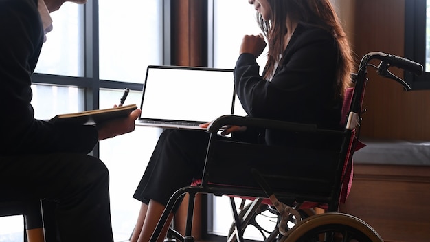 Disabled businesswoman in wheelchair working with her colleagues in office.