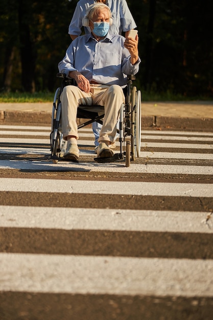 Uomo anziano disabile in sedia a rotelle sulla strada