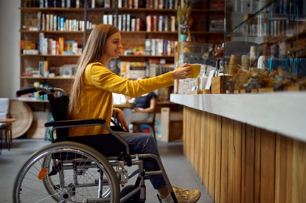 Foto studentessa disabile in sedia a rotelle in caffè