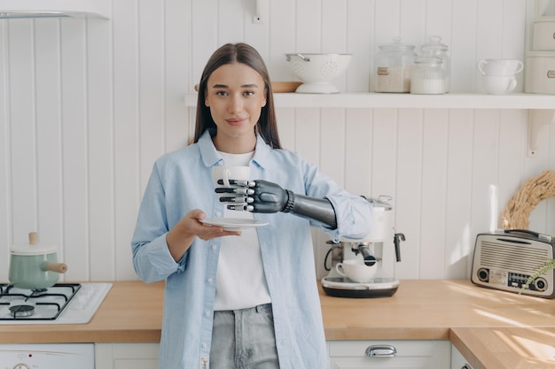 Disabled girl holding cup by bionic prosthetic arm in kitchen Lifestyle of people with disabilities