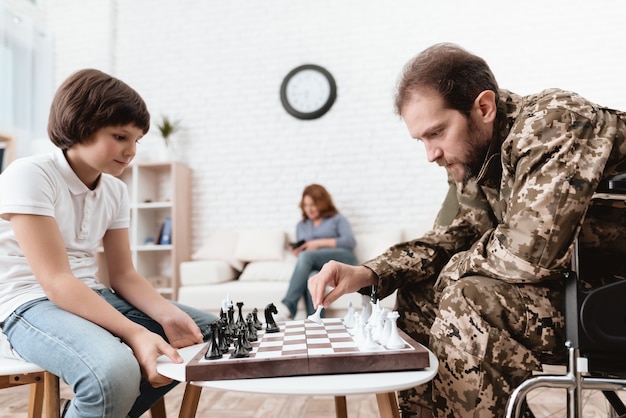 A disabled man plays with his son in chess.