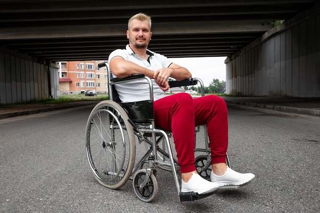 A disabled man sits in a wheelchair on the street. the concept\
of a wheelchair, disabled person, full life, paralyzed, disabled\
person, health care.