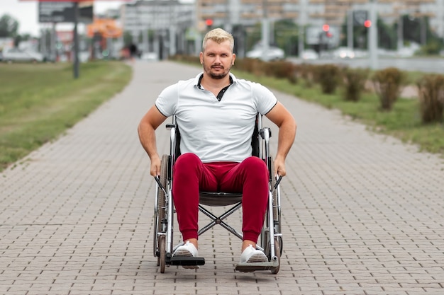 A disabled man sits in a wheelchair on the street. the concept\
of a wheelchair, disabled person, full life, paralyzed, disabled\
person, health care.