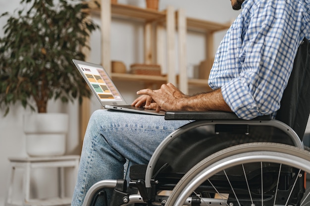 Disabled man sitting in a wheelchair and using laptop