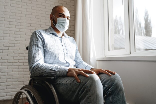 Disabled man sitting in a wheelchair and wearing face mask