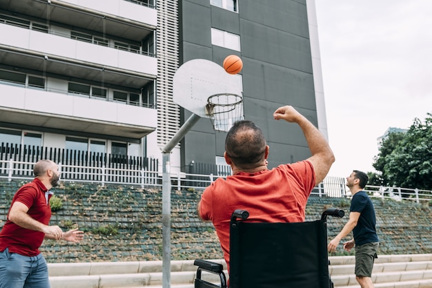 Photo disabled man throwing to basket with two friends
