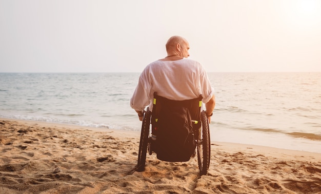 Disabled man in a wheelchair on the beach.