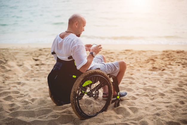 Disabled man in a wheelchair on the beach.