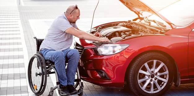 Disabled man in wheelchair check engine his car at parking