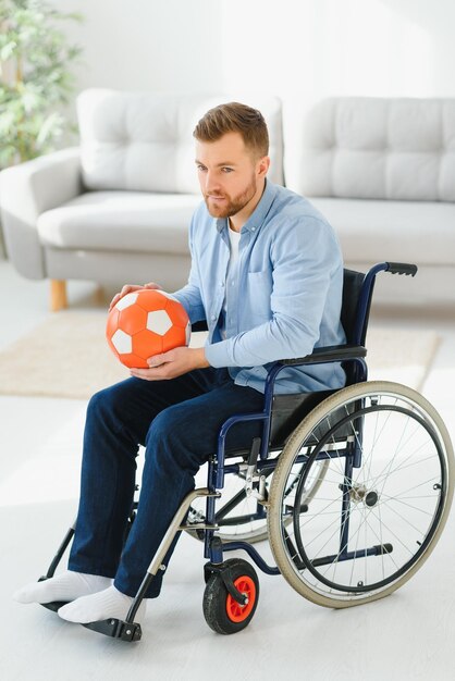 Disabled man in wheelchair holding ball with sadness cannot play game feeling depressed at home