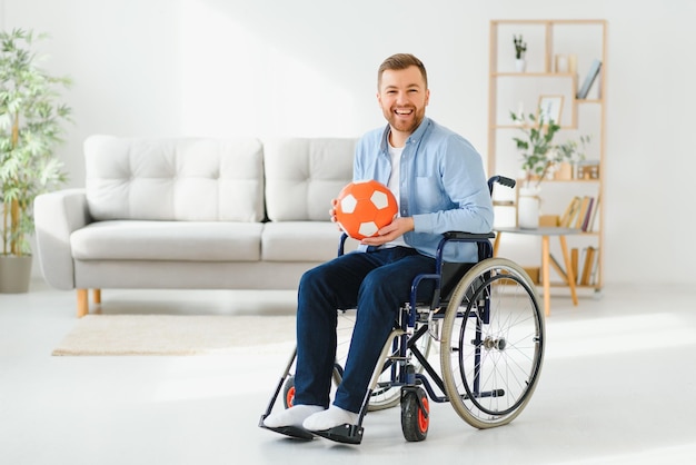 Disabled man in wheelchair holding ball with sadness cannot play game feeling depressed at home