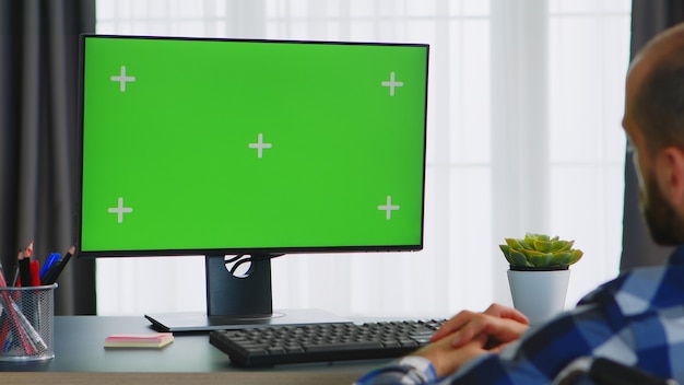 Disabled man in wheelchair looking at green screen.