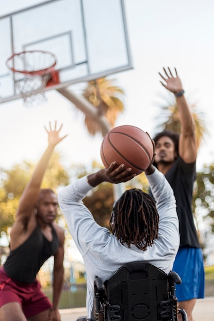 Disabled man in wheelchair playing basketball with people