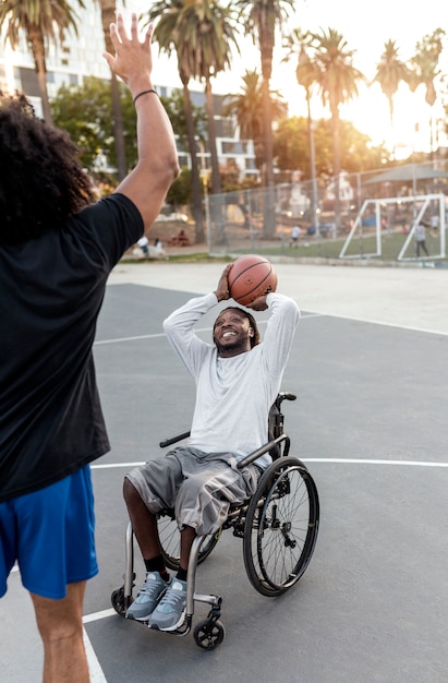 Disabled man in wheelchair playing basketball with people