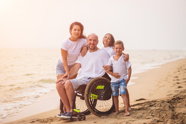 Disabled man in a wheelchair with his family on the beach.