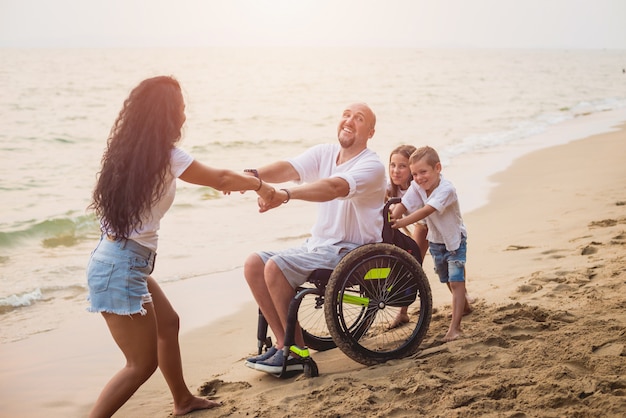 Disabled man in a wheelchair with his family on the beach.