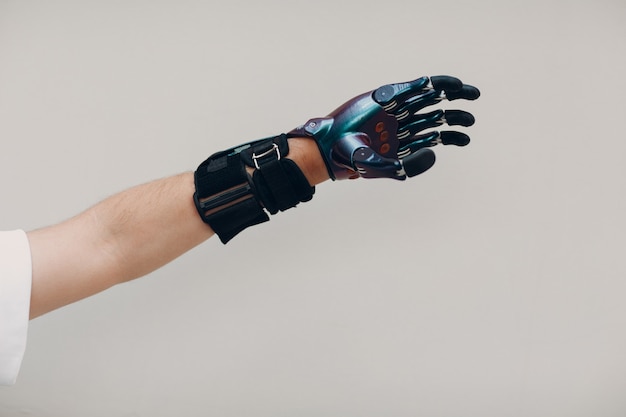 Disabled man with artificial prosthetic hand close up hand against gray background.