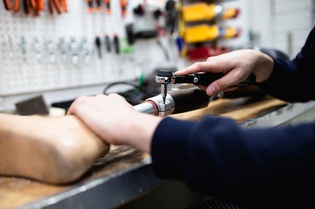 Photo disabled man working in amputee shop for production prosthetic extremity parts.