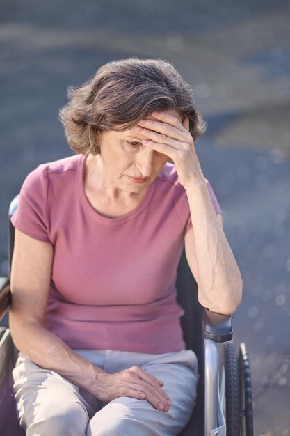 Disabled mid aged woman sitting in a wheel-chair with an
unhappy look