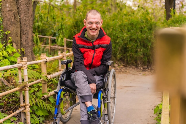 A disabled person in a public city park sitting in a wheelchair on a park path in spring