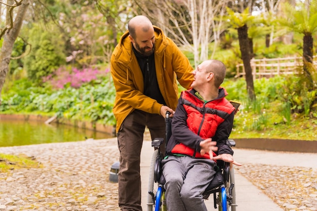 A disabled person in a public city park in the wheelchair having fun walking with a friend