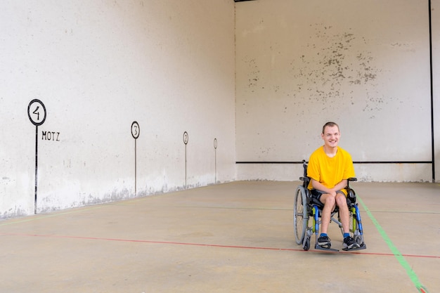 A disabled person in a wheelchair at a Basque pelota game fronton