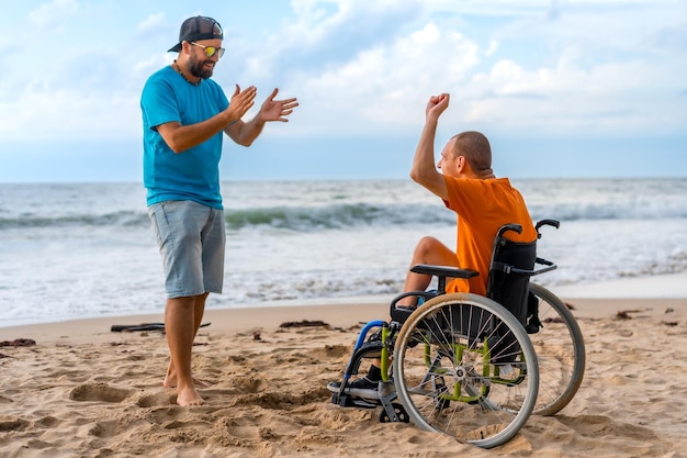 해변 에서 체어 에 앉아 있는 장애인 이 친구 와 함께 춤 을 추고 있다