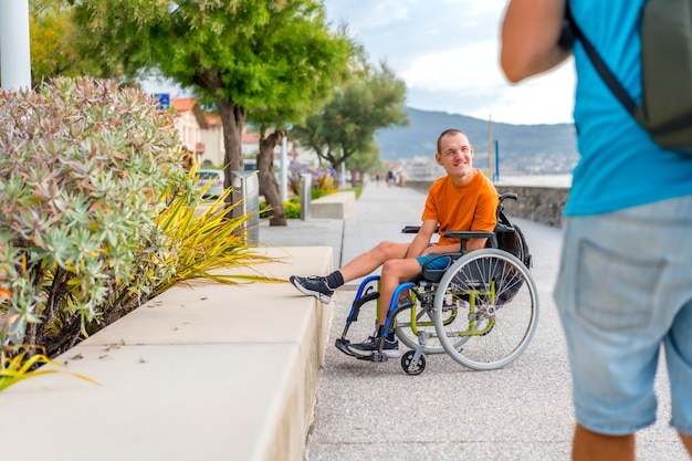 Foto una persona disabile in sedia a rotelle accanto alla spiaggia con un amico