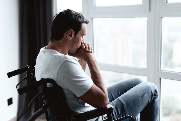 Photo disabled person in wheelchair looking at window.